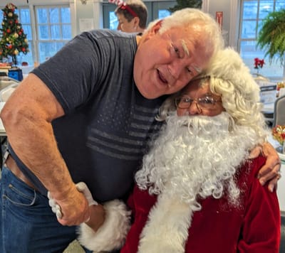 Resident dressed as Santa poses with a smiling man.