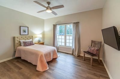 Brightly lit private resident room with a bed and window