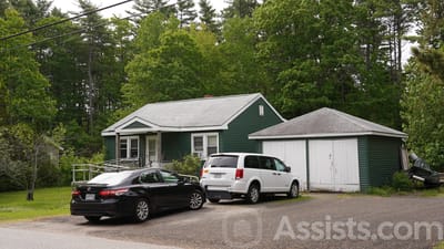 Exterior view of a small green building surrounded by trees