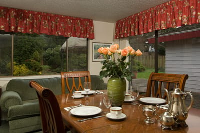 Dining area with flower vase and table settings.