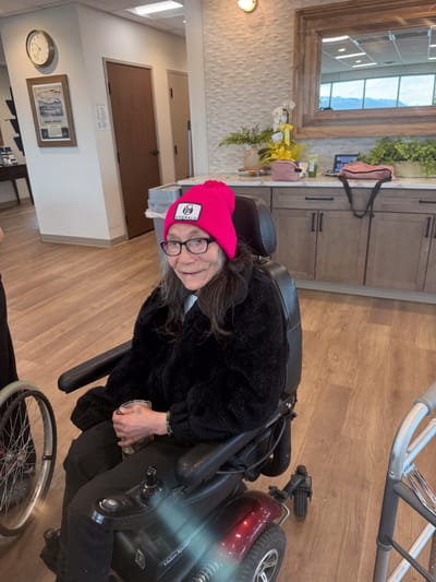 Resident in a wheelchair wearing a pink hat.