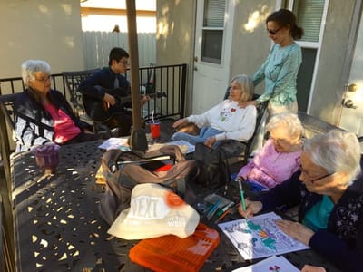 Residents enjoying an outdoor activity with a musician.