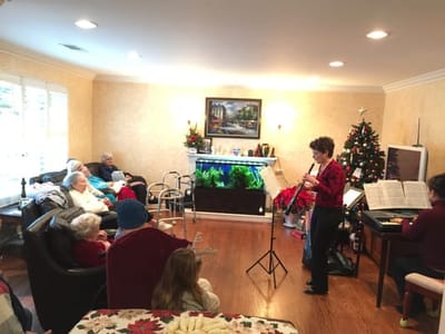 Residents enjoying a musical performance in a cozy common area.