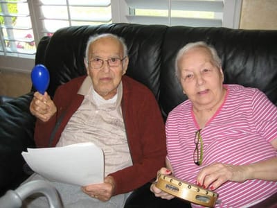 Two residents enjoying a musical activity indoors.