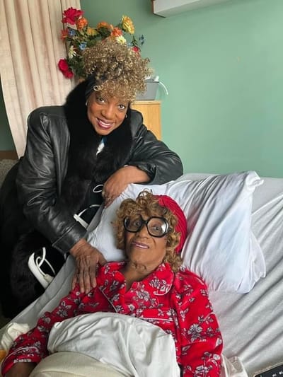 Two women smiling in a cozy room.