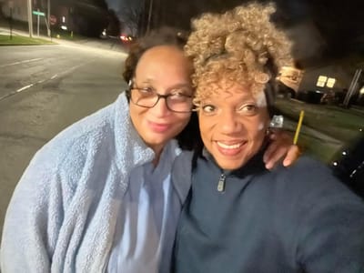 Two women posing happily outdoors at night.