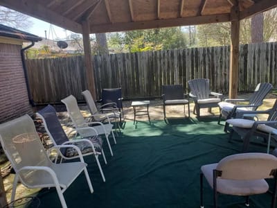 Outdoor seating area with chairs under a shelter.