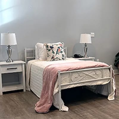 Cozy resident room with a bed and bedside table.