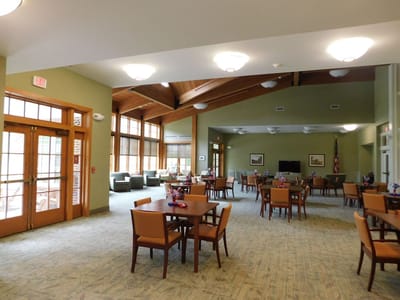 Bright common area with dining tables and large windows.