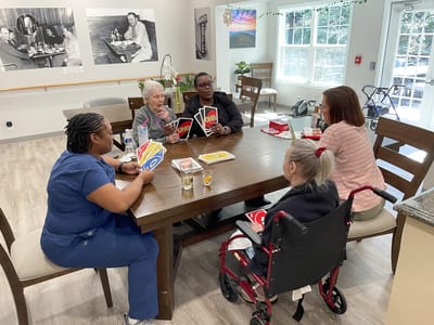 Residents engaging in a card game at a communal table.