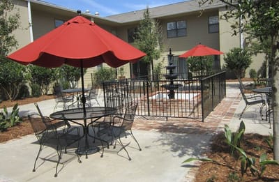 Outdoor seating area with red umbrellas and a fountain.