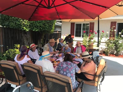 Residents enjoying a meal outdoors under a canopy.