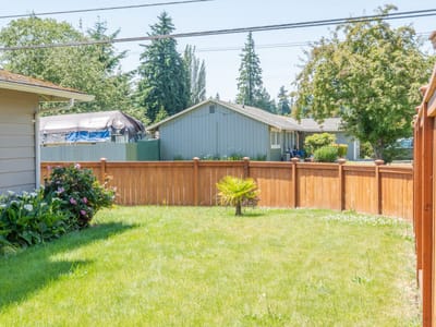 Small landscaped yard with wooden fence and grass.