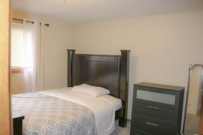 A simple bedroom with a bed and furniture.