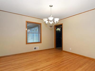 Empty interior room with hardwood floors and chandelier