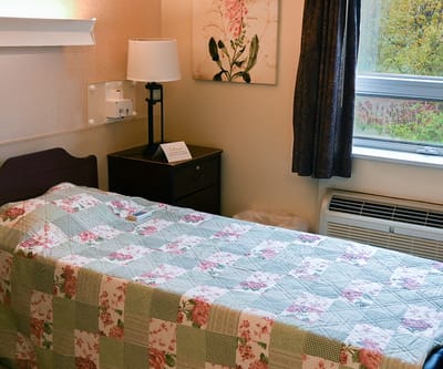 Cozy resident room with floral quilt and modern lamp