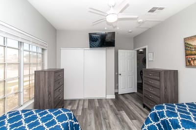 Brightly lit shared bedroom with twin beds and dressers
