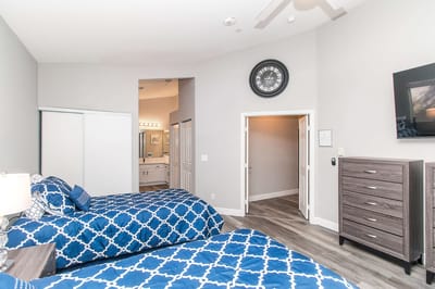 A spacious double bedroom with blue bedding and a bathroom entrance