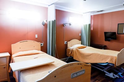 A private resident room with two beds and a TV