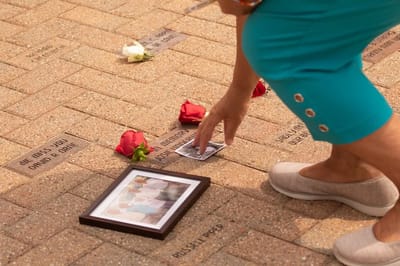Person placing flowers and a photo on a memorial.
