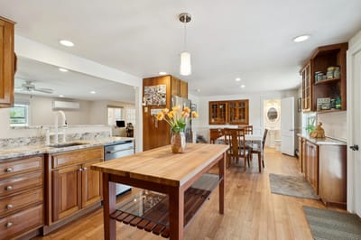 Bright kitchen with wooden cabinetry and flowers on the table.