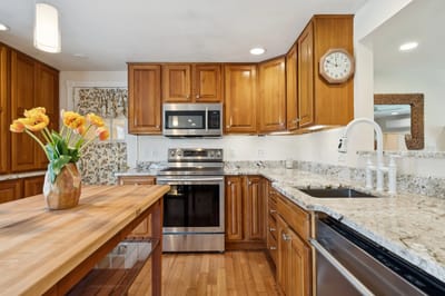 Modern kitchen with wooden cabinets and flowers.