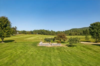 Open green space with trees and distant hills.