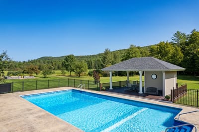 Swimming pool area with gazebo and green landscape