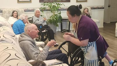 Caregiver assisting a resident in a communal area