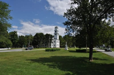 Historic building with clock tower in a park setting.