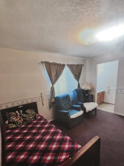 Cozy bedroom with seating area and bathroom entrance.