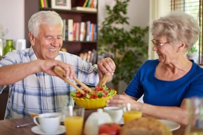 Two seniors enjoying a meal together at a dining table