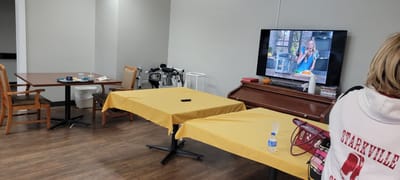 Activity room with tables, chairs, and a TV