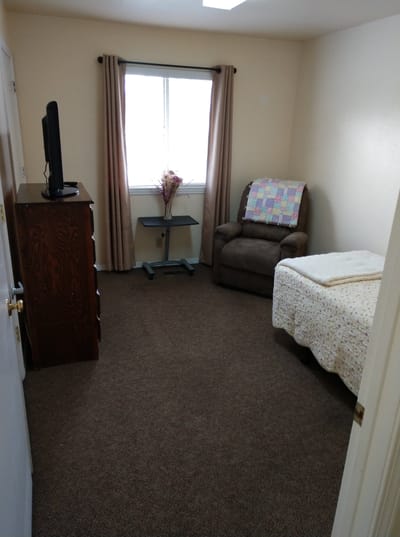 Cozy private resident room with a bed and chair