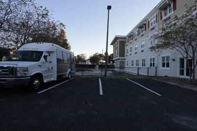 Facility exterior view with transport van and water feature