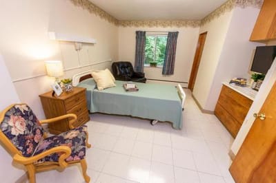 A comfortable resident room with a bed and chair