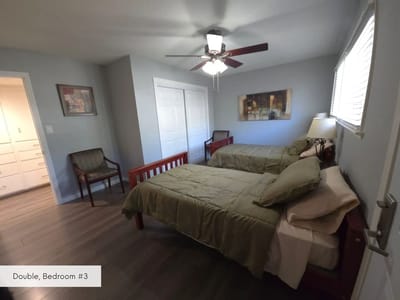 A double bedroom with two beds and a ceiling fan