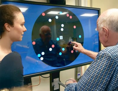A senior resident interacting with a staff member using a touchscreen