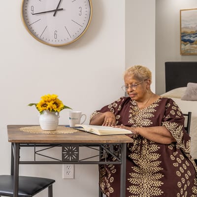 Senior resident reading at a table in a cozy room
