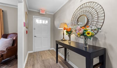 Welcoming interior hallway with flowers and mirror.