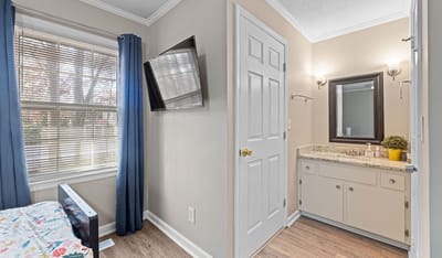 Interior view of a resident's room with a bed and vanity