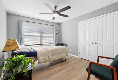 Bright private bedroom with a bed and chair.