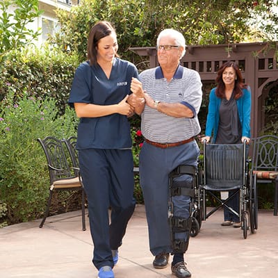 Staff assisting a resident outdoors during therapy