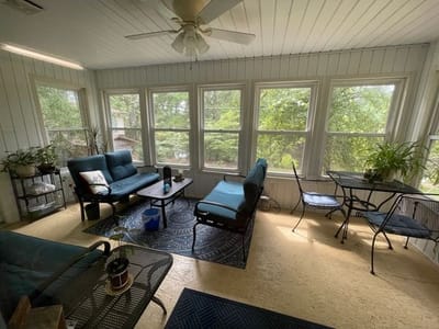 Bright sunroom with seating and greenery.
