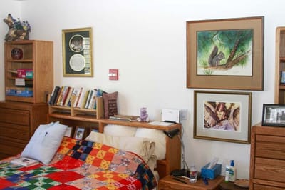 A cozy resident room with a colorful quilted bedspread