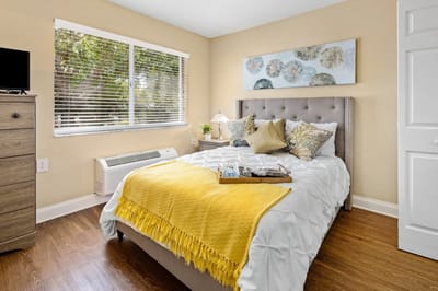 Cozy resident room with a neatly made bed and decorative pillows