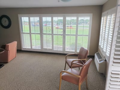A lounge area with chairs and windows overlooking green space