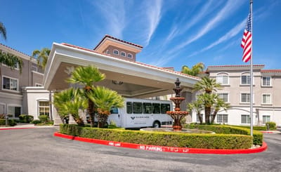 Entrance of a senior living facility with a shuttle bus.