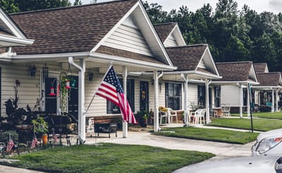 Row of cottages with American flags and garden decor.