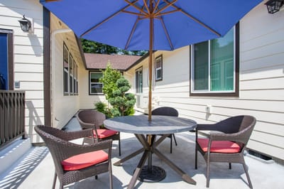 Patio area with a table and chairs under an umbrella.